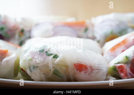 Des rouleaux de printemps sur une assiette remplie de légumes colorés. Banque D'Images