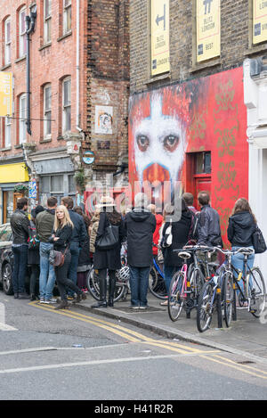 Les touristes à la recherche de l'art de mur dans le Hanbury Street, Shoreditch, London. Banque D'Images