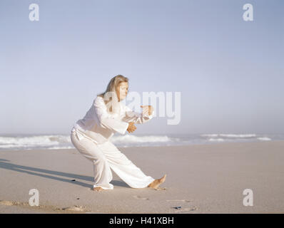 Plage de sable fin, femme, Taïchi, meilleur âge, de 50 à 60 ans, la plage, la mer, les loisirs, hobby, pratique, méditative, motion, motion, séquences, exercices, lentement, couramment, les haut-parleurs de l'ombre, "libre circulation circulation', l'équilibre, l'activité, conscience du corps, la méditation, le Tai Banque D'Images