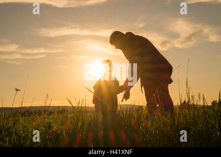 Femme et son standing in field at sunset Banque D'Images