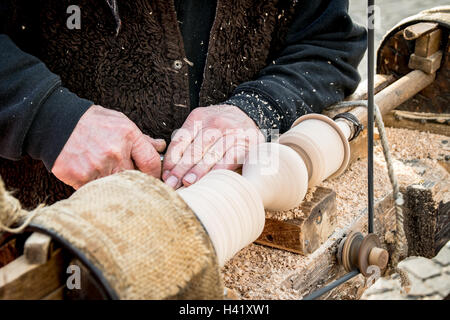 Un artisan sculpte un morceau de bois à l'aide d'une vieille tour manuel. Banque D'Images