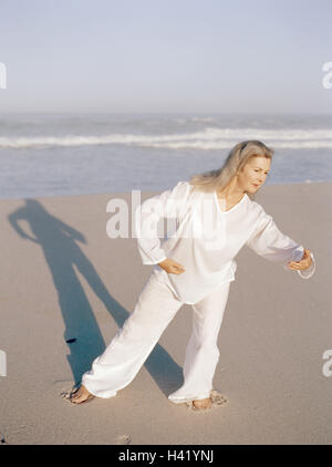 Plage de sable fin, femme, Taïchi, meilleur âge, de 50 à 60 ans, la plage, la mer, les loisirs, hobby, pratique, méditative, motion, motion, séquences, exercices, lentement, couramment, les haut-parleurs de l'ombre, "libre circulation circulation', l'équilibre, l'activité, conscience du corps, la méditation, le Tai Banque D'Images