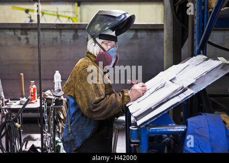 Asian worker wearing mask écrit aux formalités administratives en usine Banque D'Images