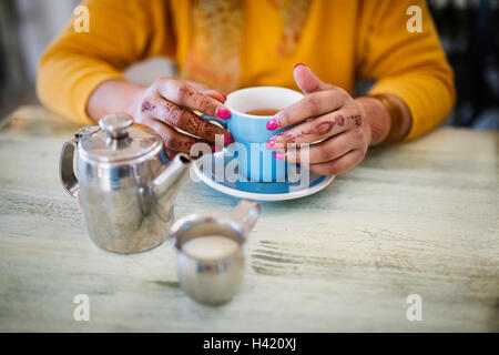 Femme avec tatouage au henné sur les mains de boire du thé Banque D'Images