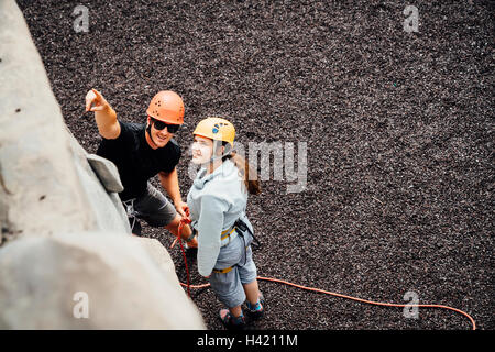 Man and Woman pointing at rock climbing wall Banque D'Images