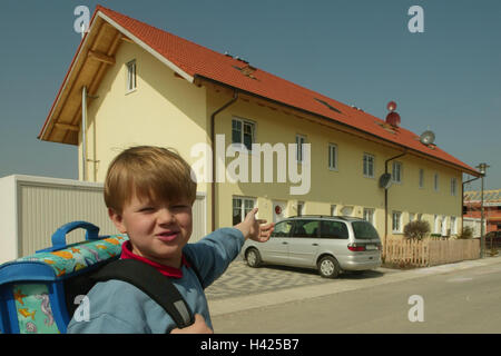 Enfant de l'école, mon garçon, le geste, la maison d'habitation à l'enfance, l'enfant, écolier, 7 ans, maison, parents, à la maison, à l'école, déclarant, montrer, indiquer, point, de la fierté, de la joie, de la chambre à la fin de la ligne, garages, parking, stationnement, voiture, voiture de tourisme, o Banque D'Images