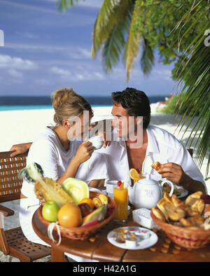 Plage, couple, prendre le petit-déjeuner, profiter, heureux, contact oculaire, modèle sorti, satisfait, homme, femme, personne, à l'extérieur, vacances, exotique, fruits, table de petit déjeuner, style de vie, de rêve, tombe amoureux, est la détente, l'harmonie, le repos, les voyages à l'étranger, des chaises, s'asseoir, plage de sable, l'océan, les Maldives, l'île, petit déjeuner, sourire, heureusement, Banque D'Images