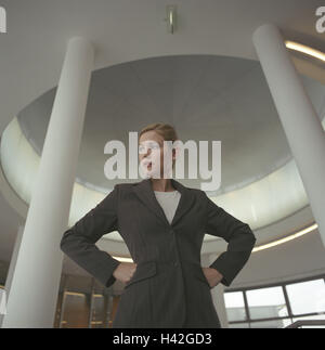 Les immeubles de bureaux, hall, businesswoman, mécontentement, douteux, détail, hall, femme, manager, 24 ans, femme, femme d'affaires, pris en charge dans les mains élégamment, hanches, avec assurance, l'auto-assurance, a décidé, de détermination, de succès, avec détermination, ambition, femme de carrière, carrière, affaires, regardez autour de vous, regardez autour de vous, examiner, de scepticisme, de pensée, d'envisager, réfléchie, à l'intérieur, de 20 à 30 ans Banque D'Images