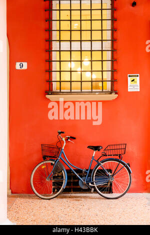 Blue location leaning on orange wall sous window Banque D'Images