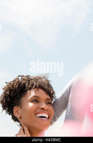 Smiling black woman rubbing neck en plein air Banque D'Images