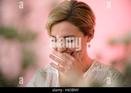 Caucasian woman couvrant la bouche en riant Banque D'Images