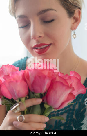 Caucasian woman smelling pink roses Banque D'Images