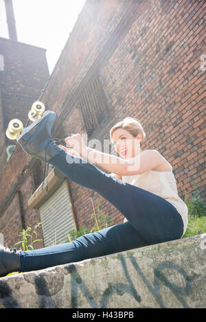 Caucasian woman lier roller skate près de brick wall Banque D'Images