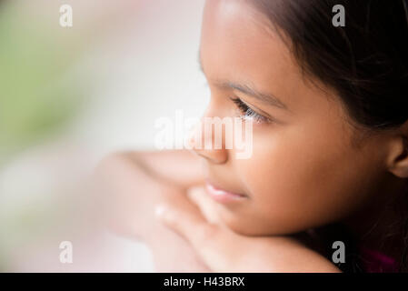 Pensive Mixed Race girl resting chin on hand Banque D'Images