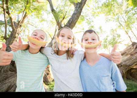 Young boy and girls smiling avec écorces de cantaloup Banque D'Images