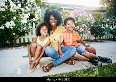 Smiling family sitting on skateboard Banque D'Images