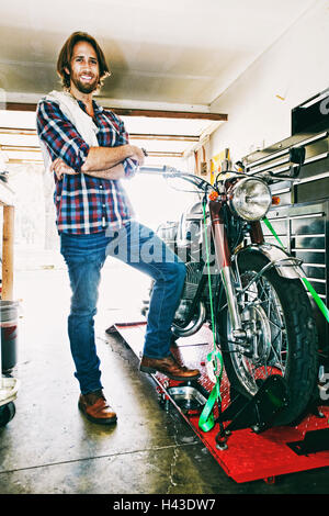Portrait homme posant avec un garage à moto Banque D'Images
