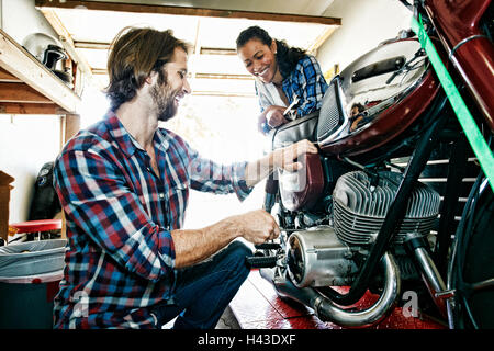 Homme Femme regardant la réparation en garage moto Banque D'Images