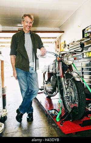 Portrait homme posant avec un garage à moto Banque D'Images