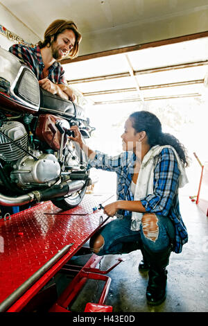 Homme Femme regardant la réparation en garage moto Banque D'Images