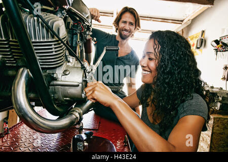 Homme Femme regardant la réparation en garage moto Banque D'Images