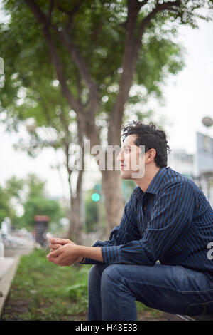 Smiling Hispanic man sitting on bench Banque D'Images