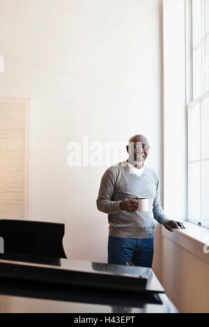 L'homme de boire du café près de window Banque D'Images