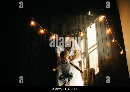 Caucasian couple hugging près de garçon sous string lights Banque D'Images