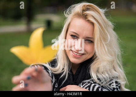 Jeune femme tenant une feuille d'automne Banque D'Images