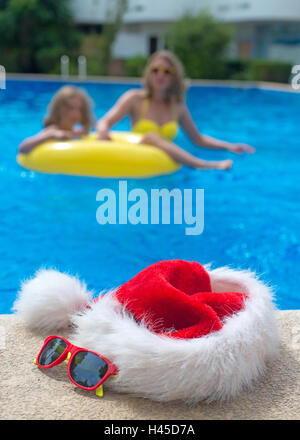 Noël rouge chapeau et des lunettes de soleil près de la piscine. Banque D'Images