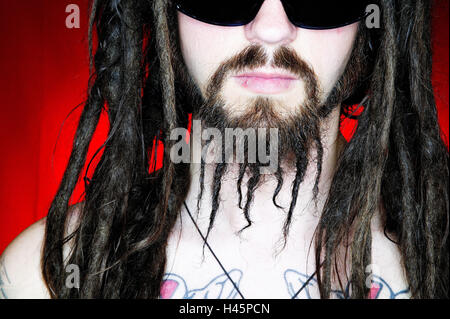 L'homme, barbe, dreadlocks, soleil, verre, sérieusement, le haut du corps librement, tatouages, Portrait, 30-40 ans, freak, gourou, poil long, Rastalocken, coiffure tendances, life attitude, style, Spiritualität, tatouages, body art, Skinhead cult, flipped out, la confiance en soi, la sérénité, l'arrière-plan rouge, abordé, studio, Banque D'Images