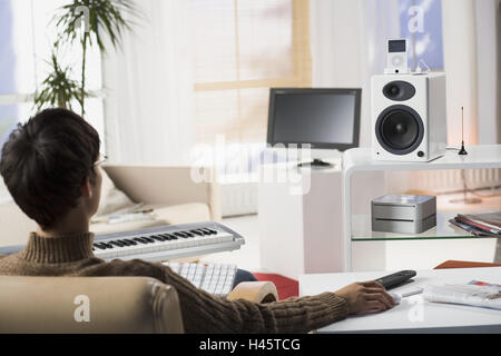 Salle de séjour, l'homme, les jeunes, assis, en vue de dos, longue distance-service, aucun des biens, personnes, série, écran, plat, LCD-TV-set, haut-parleurs, Mac mini, iPod vidéo, Apple Remote, l'électronique, électro-appareils, la technologie, Conversation, conversation-ele Banque D'Images