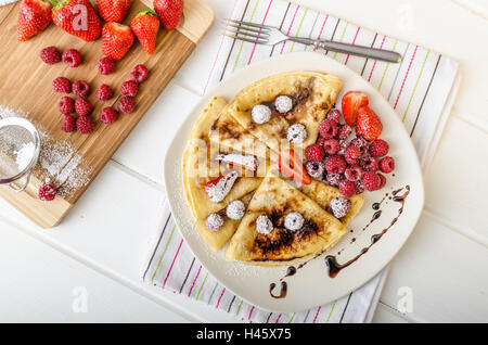 Des crêpes faites maison avec la réduction de vinaigre balsamique et de fruits frais, fraises et framboises Banque D'Images