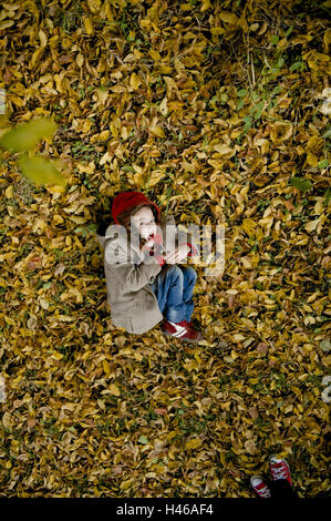 Petite fille est couchée sur feuillage de l'automne, Banque D'Images