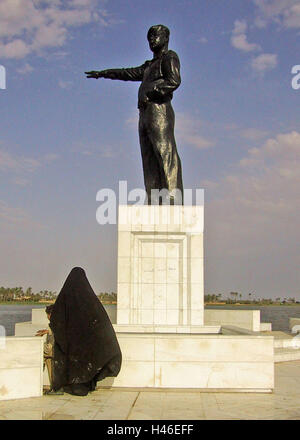 13 avril 2003 une femme irakienne se distingue avec son enfant en dessous d'une statue de Saddam Hussein dirigé vers l'Iran sur le Chatt al-Arab à Bassorah. Banque D'Images