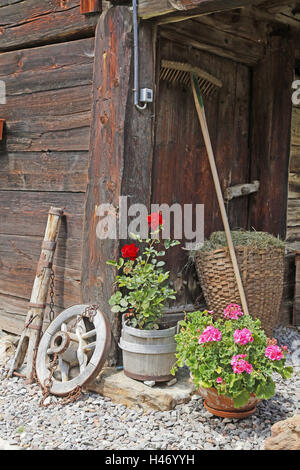 Maison en bois, le râteau, le panier, la roue, les outils agricoles en face de vieille maison de bois, grange Banque D'Images