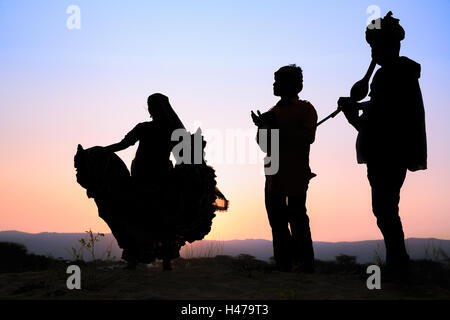 Coucher du soleil, la silhouette d'une femme gitane danse une danse traditionnelle avec deux musiciens, Pushkar, Rajasthan, India Banque D'Images