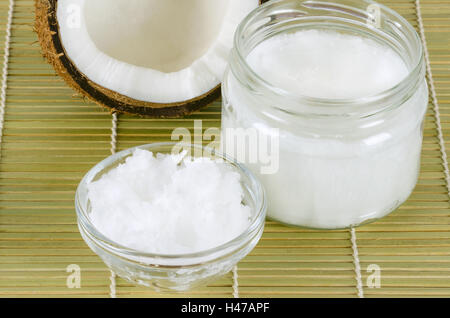 L'huile de noix de coco dans les verres sur le tapis de bambou horizontal. Extra vierge biologique huile de coprah. L'huile comestible, extrait de viande de coco. Banque D'Images