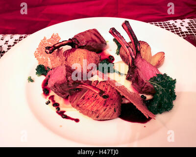 Selle de chevreuil grillé servi avec des os avec pommes de terre rôties, sauce on white plate Banque D'Images