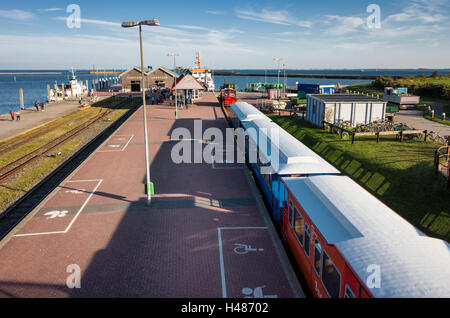 Schiffahrt Langeoog. Deutschland Allemagne. Le train est à côté de la plate-forme du port alors que les passagers se précipitent vers le traversier d'attente amarrés sur la jetée. C'est le principal système de transport pour les touristes à visiter et quitter l'île. Banque D'Images