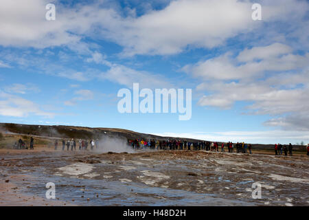 Les gens se tenant sur les armes chimiques et les dépôts géologiques causés par le débordement de l'eau du geyser geysir Islande Banque D'Images