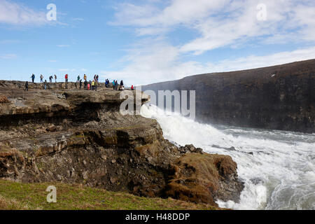 Les touristes sur la plate-forme de roche surplombant la cascade de Gullfoss dans le cercle d'or l'Islande Banque D'Images