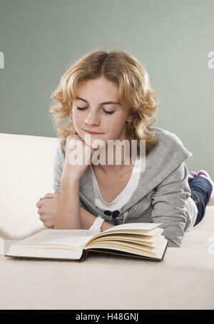 Girl se trouve sur le canapé et lit un livre, Banque D'Images