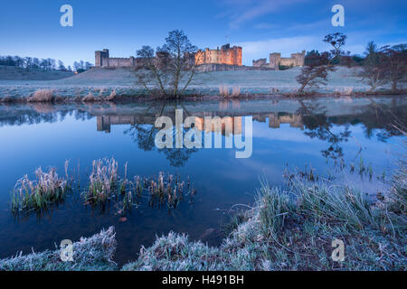 Château d'Alnwick reflétée dans la rivière Aln sur un matin d'hiver glacial, Northumberland, Angleterre. L'hiver (mars) 2014. Banque D'Images