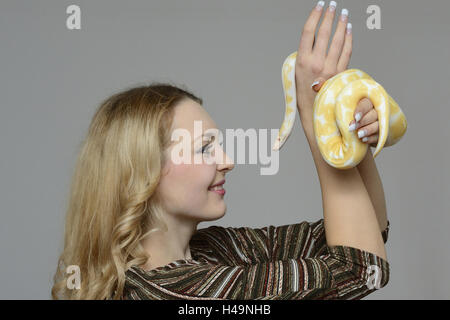 Jeune femme, tiger's python, Python molurus, albino, tenir, sourire, portrait, sur le côté, Banque D'Images