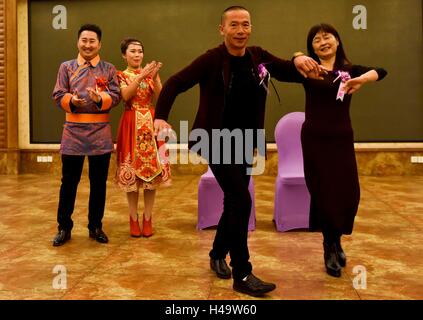 Tacheng, la Région Autonome Uygur du Xinjiang. 9 octobre, 2016. Mariée Kong du Ning (2L) Père (2e R) et la mère (1re l) exécuter la danse folklorique de reconnaître tous les invités pendant le mariage à Tacheng, nord-ouest de la Chine, la Région autonome du Xinjiang Uygur, Octobre 9, 2016. Kong Ning, demi-groupe ethnique Xibe et demi-groupe ethnique Daur, mariée et son époux Ding Chenhao du groupe ethnique mandchou a tenu un grand mariage coloré et mélangé à la fois traditionnelle et de l'ouest de la douane dans la ville frontière de Tacheng, bénéficiant d'un doux début de leur mariage. © Zhao Ge/Xinhua/Alamy Live News Banque D'Images