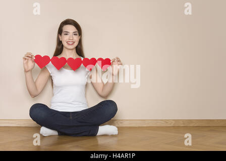 Femme coupe papier cœur dans ses mains, heureux, sourire, Banque D'Images