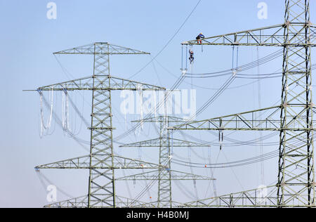 Poteaux à haute tension, les fils, l'installation de la ligne d'alimentation, l'homme grimpe à bras latéral sur lequel un autre homme travaille, Banque D'Images