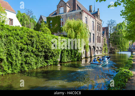 BRUGES, BELGIQUE - 6 avril 2008 : les touristes flottent sur un bateau à travers le canal près de gîtes Dijver Banque D'Images