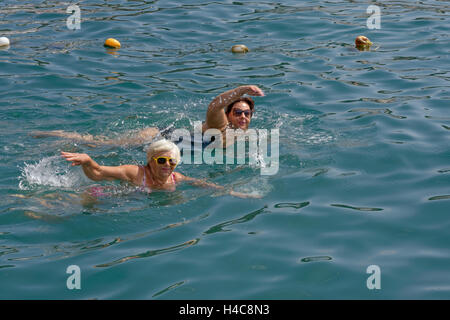 Deux femmes, blonde et brune dodue mature, nagent dans l'eau claire de la mer. Banque D'Images